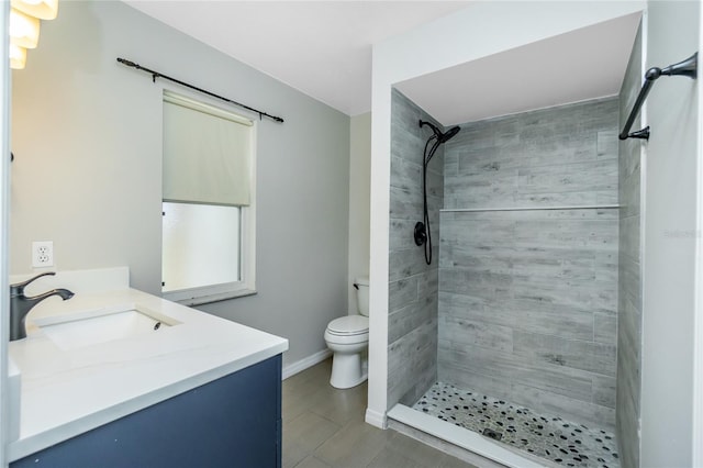 bathroom featuring baseboards, vanity, toilet, and tiled shower