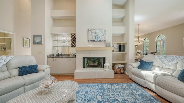 4691 Las Brisas Ln, Sarasota, FL 34238 - living area featuring a towering ceiling, wood finished floors, built in shelves, a tiled fireplace, and a notable chandelier
