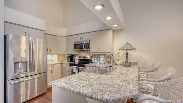 4691 Las Brisas Ln, Sarasota, FL 34238 - kitchen with appliances with stainless steel finishes, a sink, a peninsula, a kitchen bar, and backsplash