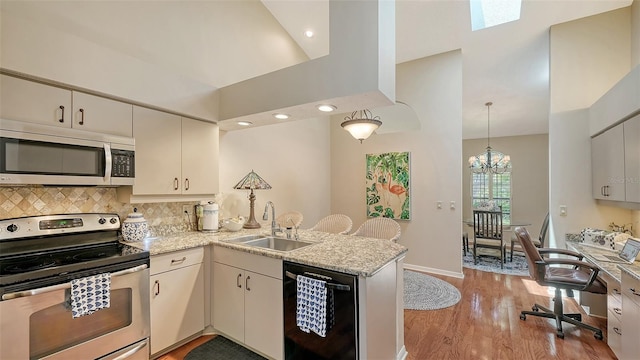 4691 Las Brisas Ln, Sarasota, FL 34238 - kitchen with a peninsula, a chandelier, a sink, light wood-style flooring, and appliances with stainless steel finishes