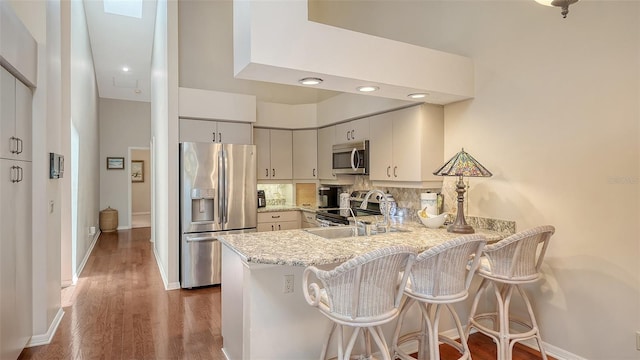 4691 Las Brisas Ln, Sarasota, FL 34238 - kitchen featuring a peninsula, appliances with stainless steel finishes, a sink, and wood finished floors