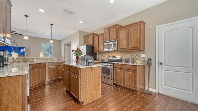 5403 Mang Pl, Sarasota, FL 34238 - kitchen with wood tiled floor, brown cabinets, tasteful backsplash, and stainless steel appliances