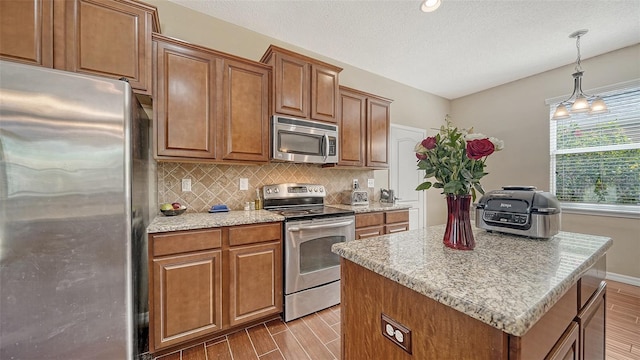 5403 Mang Pl, Sarasota, FL 34238 - kitchen with brown cabinets, stainless steel appliances, decorative backsplash, and wood finished floors
