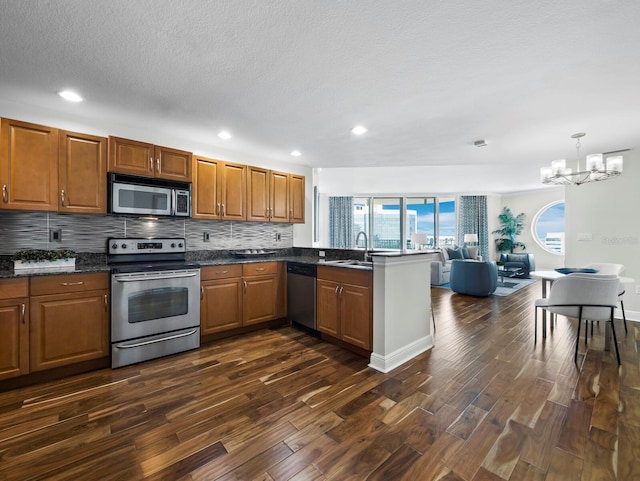 1771 Ringling Blvd Unit 1104, Sarasota, FL 34236 - kitchen featuring stainless steel appliances, an inviting chandelier, dark wood-style floors, and tasteful backsplash