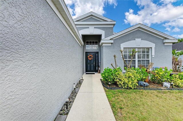 doorway to property featuring stucco siding and a yard