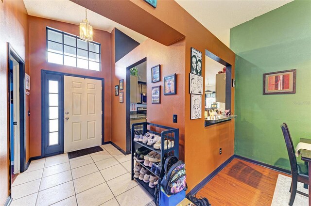 entrance foyer with a chandelier, baseboards, and light tile patterned floors