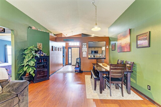 dining area with vaulted ceiling, wood finished floors, wine cooler, and baseboards