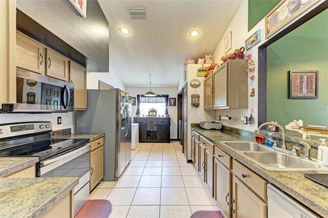 kitchen with stainless steel appliances, a sink, a textured ceiling, light tile patterned floors, and light countertops