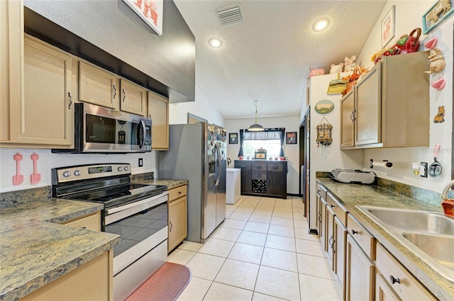 kitchen featuring stainless steel appliances, a textured ceiling, a sink, light tile patterned floors, and light brown cabinets