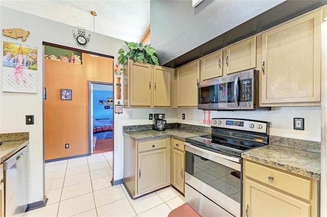 kitchen with stainless steel appliances, light tile patterned floors, baseboards, and cream cabinetry