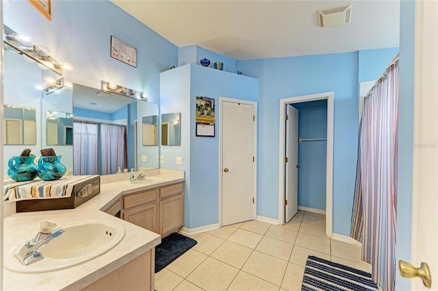 bathroom with double vanity, tile patterned flooring, and baseboards
