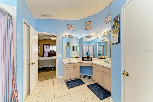 ensuite bathroom with ceiling fan, tile patterned flooring, double vanity, and baseboards