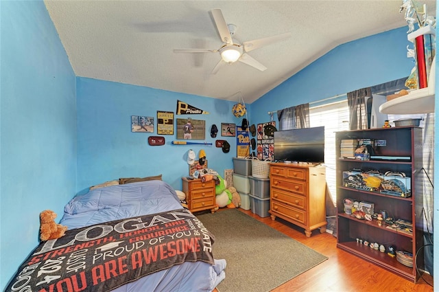 bedroom featuring lofted ceiling, wood finished floors, a textured ceiling, and ceiling fan