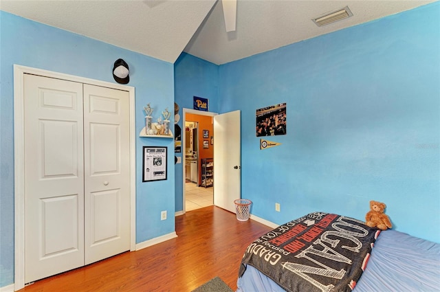 bedroom with wood finished floors, a closet, baseboards, and a ceiling fan
