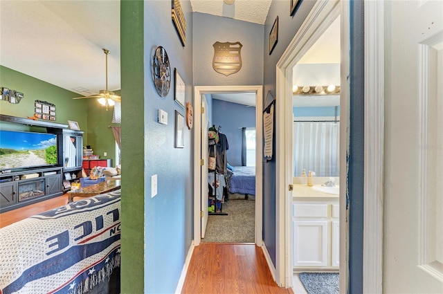 hallway featuring wood finished floors, baseboards, and a sink
