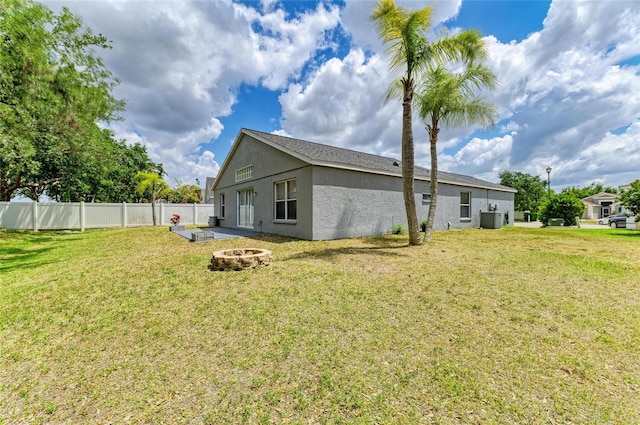 rear view of house with a fire pit, stucco siding, and central AC unit