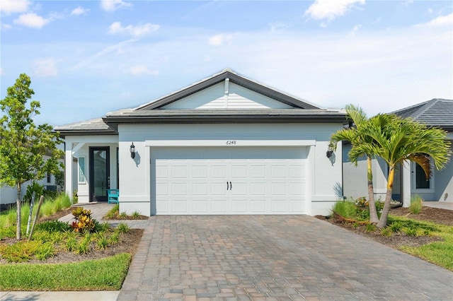 ranch-style home featuring a garage, decorative driveway, and stucco siding