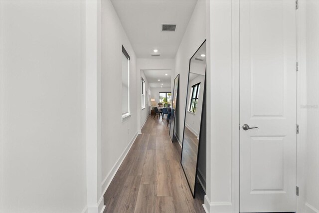 hallway featuring wood finished floors, recessed lighting, and baseboards