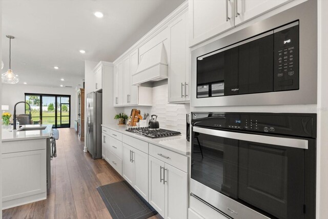 kitchen with appliances with stainless steel finishes, a sink, custom exhaust hood, recessed lighting, and white cabinetry