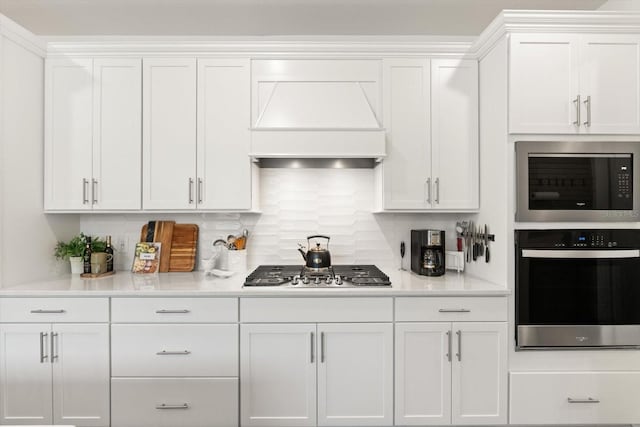 kitchen with appliances with stainless steel finishes, white cabinets, custom exhaust hood, and light countertops