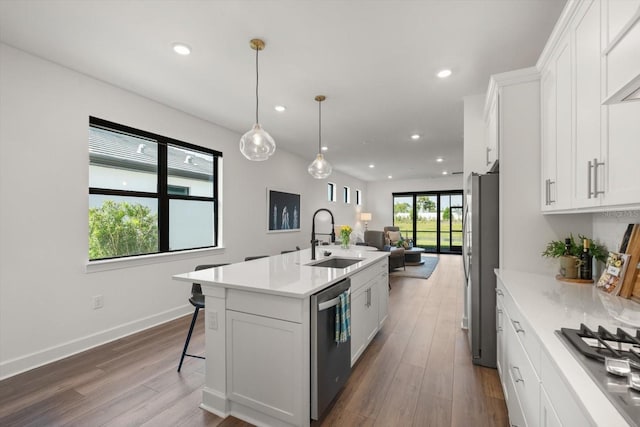 kitchen with a sink, stainless steel appliances, open floor plan, dark wood-style flooring, and light countertops
