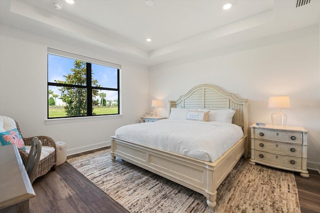 bedroom featuring a raised ceiling, wood finished floors, baseboards, and recessed lighting