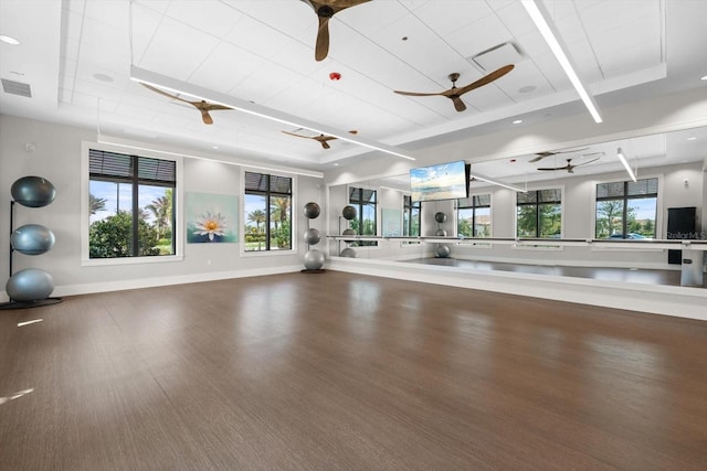 workout room featuring a ceiling fan, wood finished floors, a raised ceiling, and baseboards