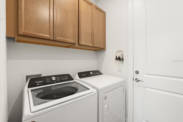 clothes washing area featuring separate washer and dryer and cabinet space
