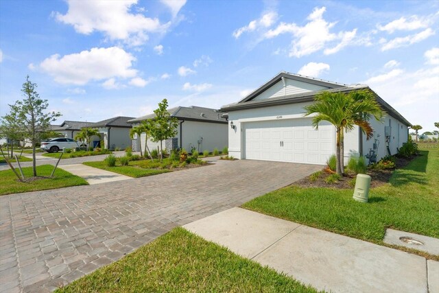 single story home with decorative driveway, a garage, a front lawn, stucco siding, and a residential view