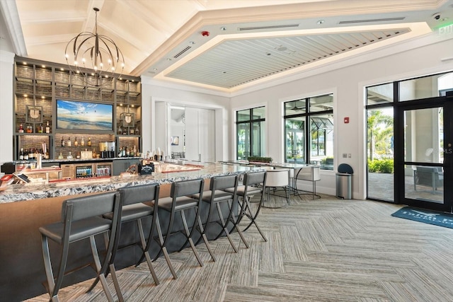 indoor wet bar with light colored carpet, a chandelier, lofted ceiling, and baseboards