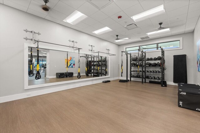 exercise room with a paneled ceiling and baseboards