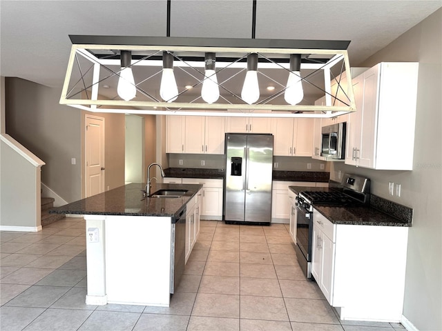 kitchen featuring a sink, light tile patterned floors, white cabinets, dark stone countertops, and stainless steel appliances