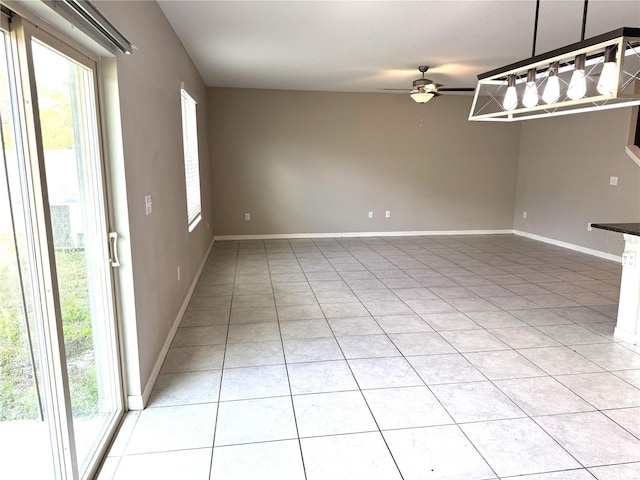 unfurnished room featuring a healthy amount of sunlight, light tile patterned floors, baseboards, and a ceiling fan