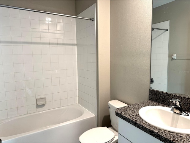 bathroom featuring vanity, a textured wall, tub / shower combination, and toilet