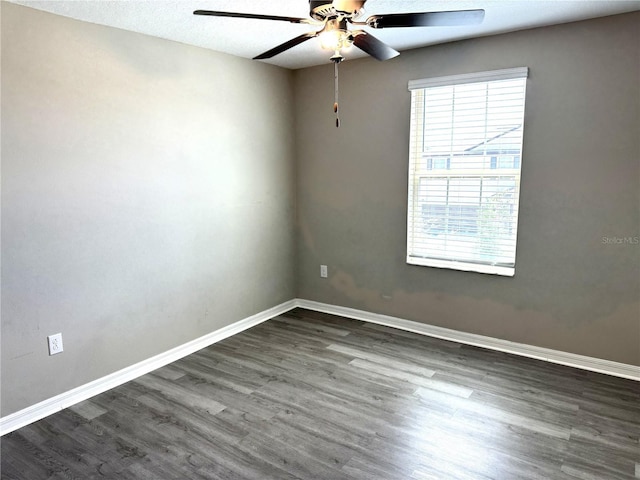 empty room featuring baseboards, ceiling fan, and dark wood-style floors