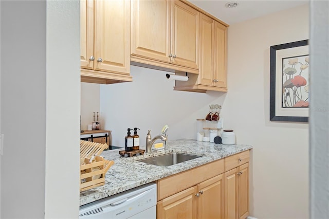 kitchen featuring white dishwasher, light stone countertops, light brown cabinets, and a sink