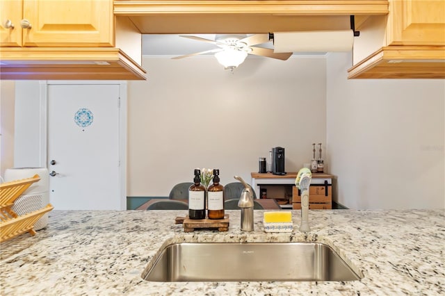 kitchen with light stone countertops, a ceiling fan, light brown cabinetry, and a sink