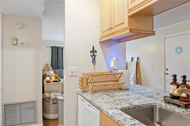 kitchen with light brown cabinetry, visible vents, a sink, white dishwasher, and light stone countertops