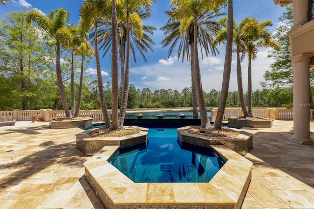 outdoor pool with a water view, a hot tub, and a patio area