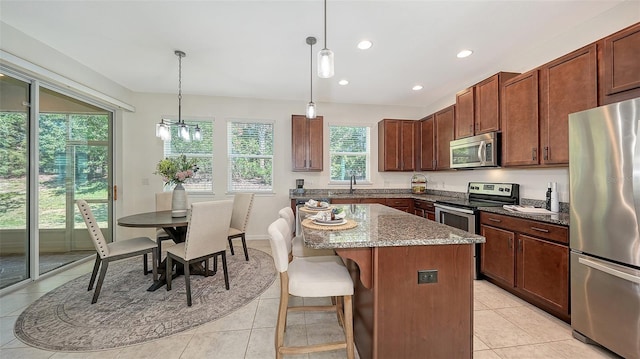 11847 Meadowgate Pl, Lakewood Ranch, FL 34211 - kitchen featuring a center island, stone counters, light tile patterned flooring, and appliances with stainless steel finishes