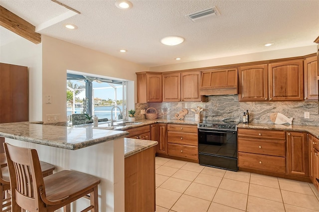 621 Ivanhoe Ln, Holmes Beach, FL 34217 - kitchen featuring black range with electric stovetop, custom range hood, a kitchen bar, backsplash, and visible vents