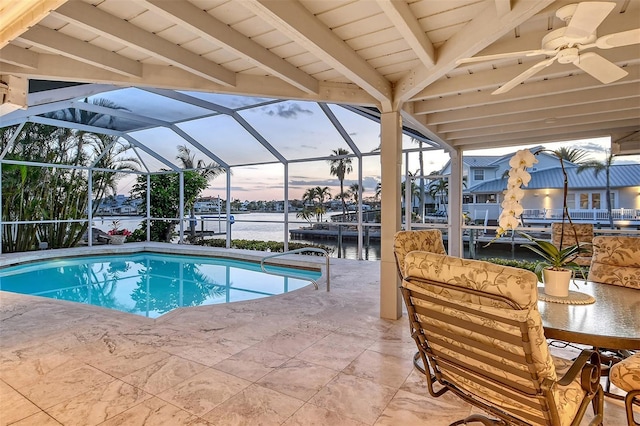 621 Ivanhoe Ln, Holmes Beach, FL 34217 - pool at dusk featuring an outdoor pool, a water view, a ceiling fan, a patio, and a lanai
