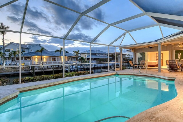 621 Ivanhoe Ln, Holmes Beach, FL 34217 - outdoor pool featuring glass enclosure, a boat dock, boat lift, a patio, and a residential view
