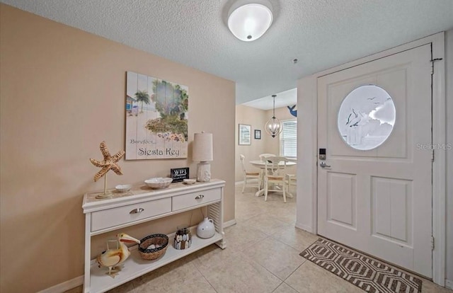 entryway featuring baseboards, a textured ceiling, and light tile patterned floors