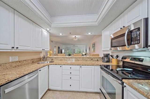kitchen featuring a sink, appliances with stainless steel finishes, white cabinetry, and a raised ceiling