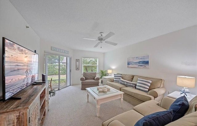 living area featuring carpet flooring, a textured ceiling, and a ceiling fan