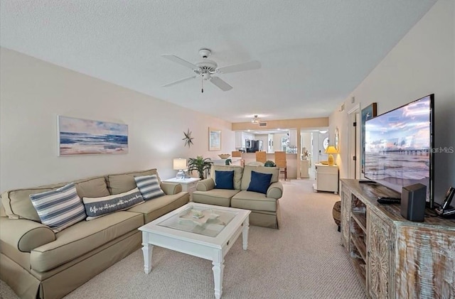 carpeted living area featuring a ceiling fan and a textured ceiling