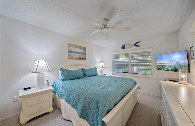 bedroom with baseboards, a ceiling fan, a textured ceiling, and light colored carpet