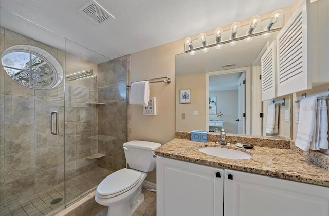 full bathroom with vanity, a shower stall, toilet, and visible vents