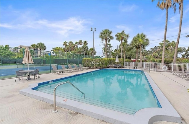 community pool with fence and a tennis court